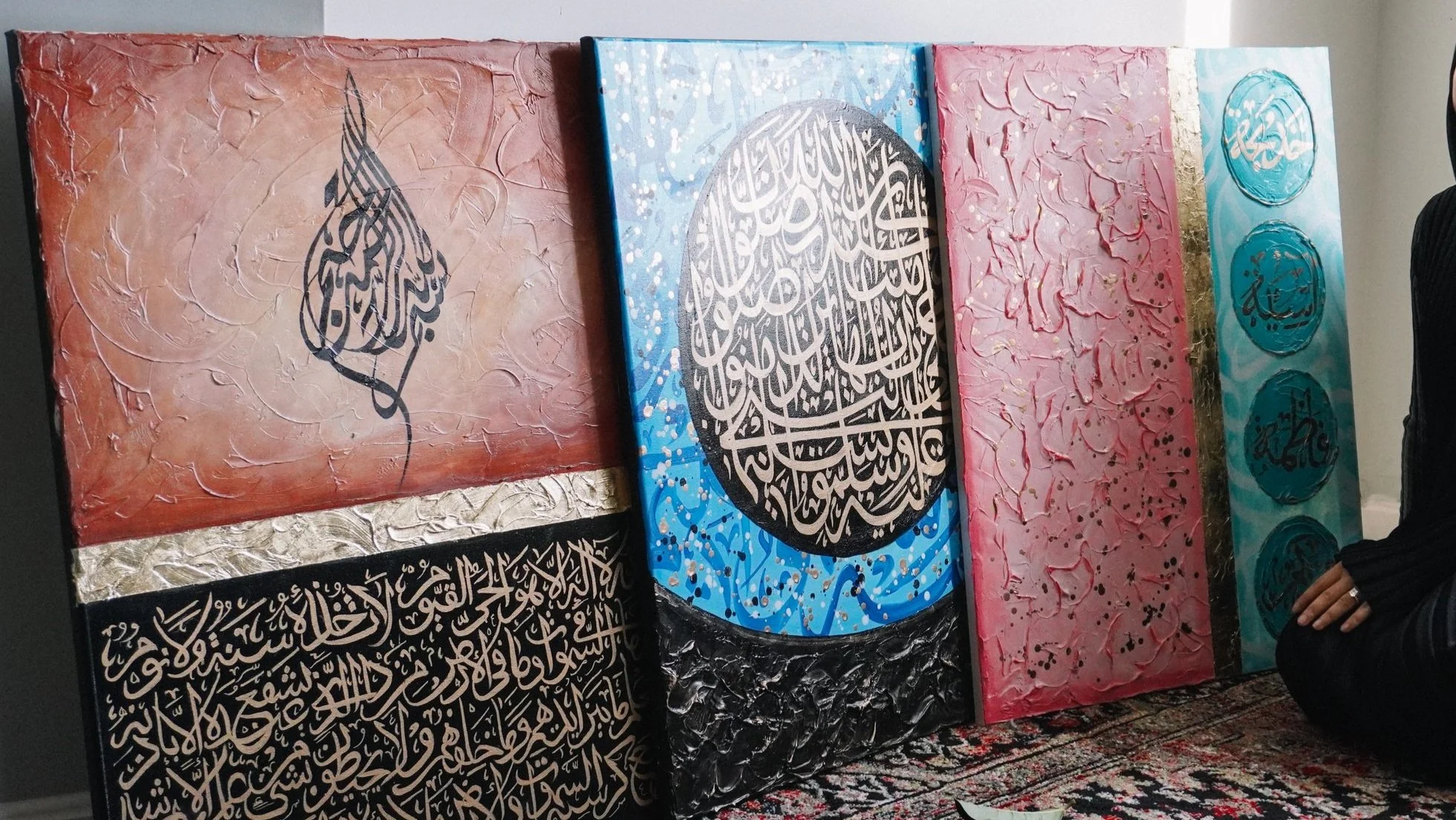 Collection of five colorful abstract paintings with Arabic calligraphy, textured backgrounds, and decorative elements on display in an art gallery.